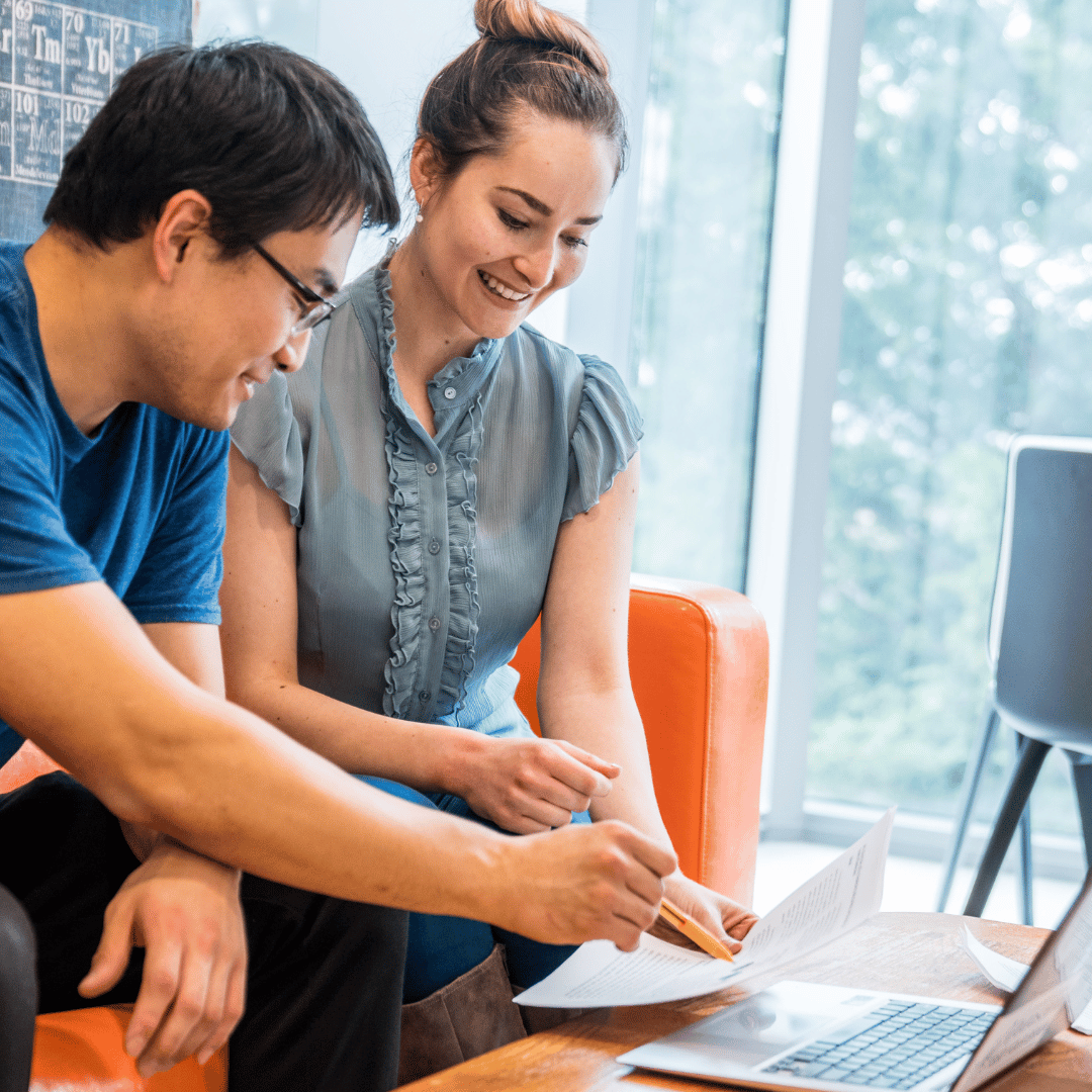 image of two individuals looking at a computer smiling.